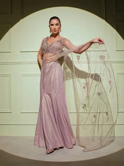 Captured in the spotlight, this mauve fish-cut gown features a sheer embroidered cape, adding a layer of ethereal beauty to the structured silhouette.