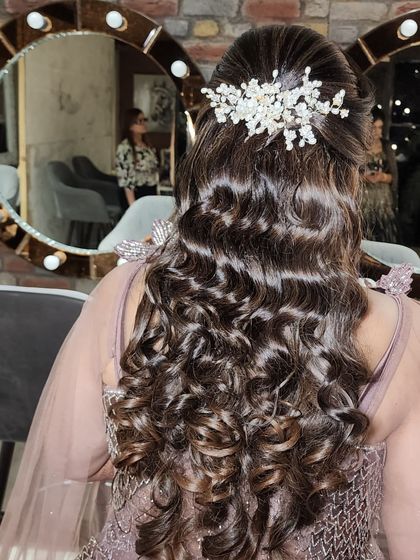 The details matter. This hairstyle combines soft curls with a beautifully placed hairpiece, creating an elegant and romantic look for any special occasion.