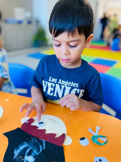 A close-up on a student adding googly eyes to his craft, a fun part of the creative process.