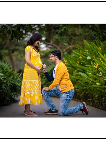 A playful and loving moment as the dad-to-be kneels to "listen" to the baby bump with a stethoscope.