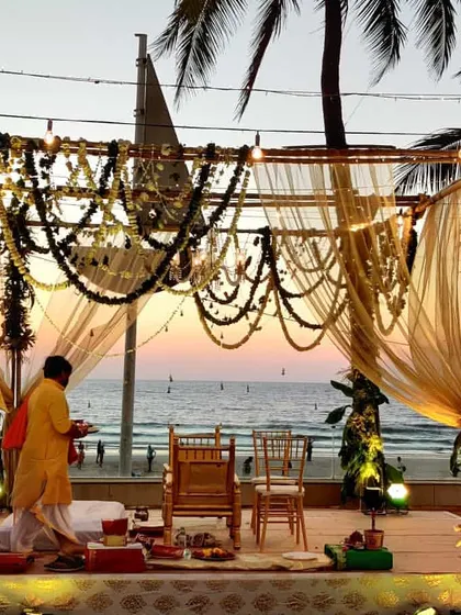 A beautiful shot of the priest preparing for the ceremony at our rustic beach mandap. The setting sun and the gentle drapes create a serene and spiritual ambiance.