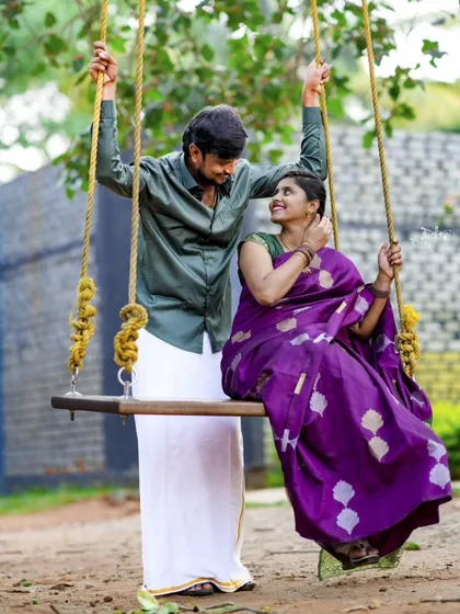 A sweet moment on a swing. The bride's purple silk saree looks vibrant against the natural background in this classic pre-wedding pose.