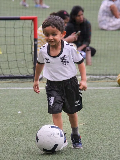 The smile on this young player's face says it all. He enjoys learning fundamental skills, dribbling with confidence and joy.