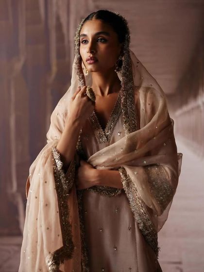 A close-up portrait capturing the soft, ethereal quality of a sheer dupatta. The styling focuses on creating a gentle and romantic mood, perfect for a bridal lookbook.