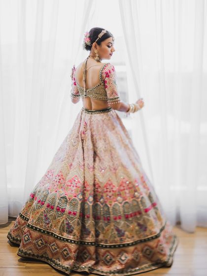 A beautiful back shot of the bride, showcasing the detailed embroidery of her blouse and her elegant hairstyle.