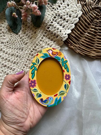 A yellow oval frame magnet adorned with little birds and flowers.