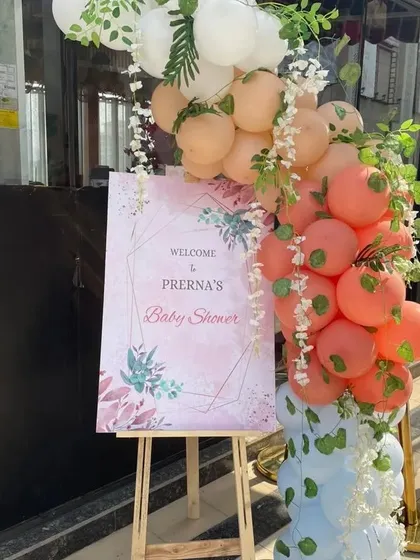 A welcome easel for a baby shower, decorated with a beautiful balloon garland in pastel colors.