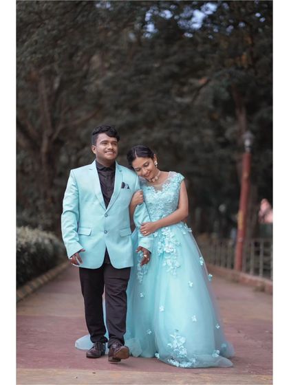 A candid moment of a couple walking together. The man's light blue suit perfectly complements the woman's floral applique ball gown, creating a coordinated and stylish look.