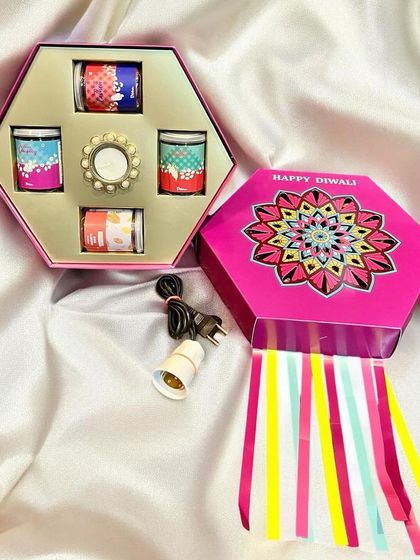 A unique hexagonal gift box for Diwali that opens up to reveal a set of four colorful scented candles. The box itself is designed to be used as a festive lantern.