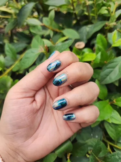 Love for black never fades. This design on natural nails uses a black base with holographic chrome and foil accents for a dark, edgy look.