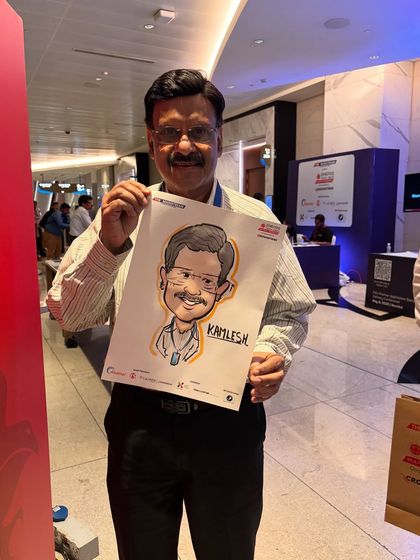 A smiling guest with his finished portrait at the Jio World Convention, a great example of a branded event souvenir.