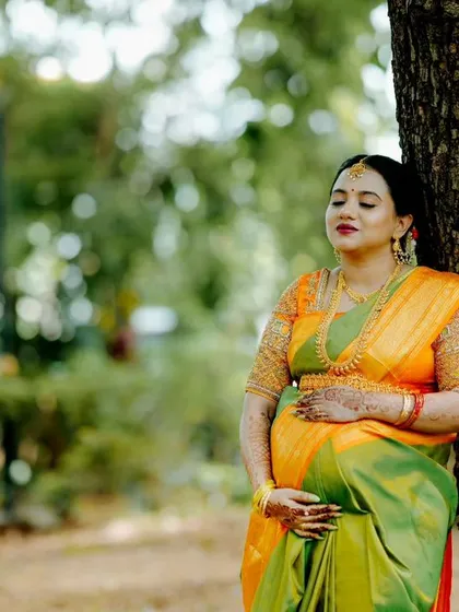 A serene solo maternity portrait of a mother-to-be in a vibrant silk saree, taken in a peaceful park setting. The focus is on capturing the calm and beautiful glow of pregnancy.