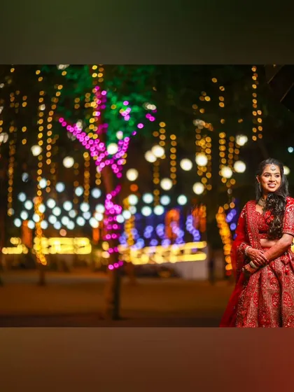 An artistic shot of the bride against a backdrop of fairy lights, her red lehenga creating a magical look.
