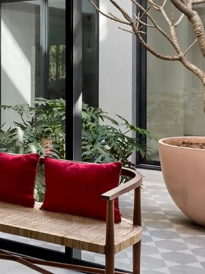 Bright red cushions add a pop of color to this serene courtyard seating area. The space is designed as an intimate outdoor room, perfect for quiet reflection.