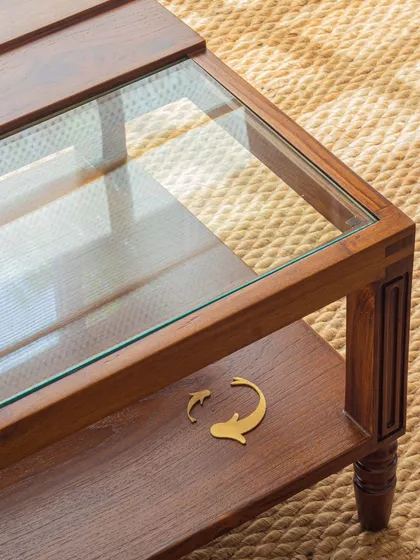 A detail of the Kulam center table, showing the charming brass fish inlay on the lower shelf. This small touch adds to the story of the piece, recalling memories of watching fish swim in a tranquil temple pond.