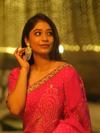 Adjusting her earring against a backdrop of golden bokeh lights, this portrait captures a classic, elegant moment during the Dev Deepawali festival.