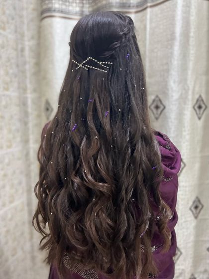 A half-up style with a waterfall braid and long, flowing curls, decorated with pearl accessories for a dreamy look.