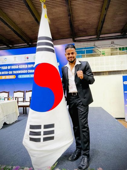 Standing proudly with the Korean flag, the symbol of Taekwondo's origin.