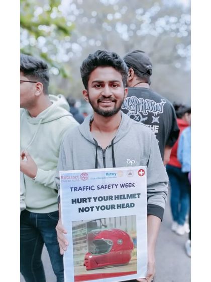 Holding a poster that says "Hurt your helmet not your head." A simple but powerful message.