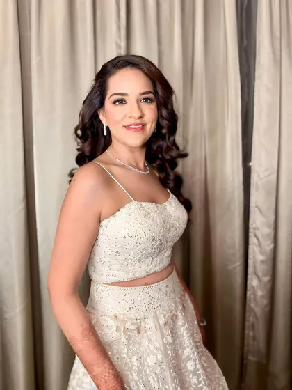 A full-length view of the client in her beautiful white sangeet outfit. The soft, cascading curls add a romantic and elegant touch to her overall look.