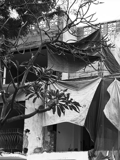 The facade of a building mid-renovation, partially covered by tarps. Even in this raw state, the new architectural forms are beginning to emerge.