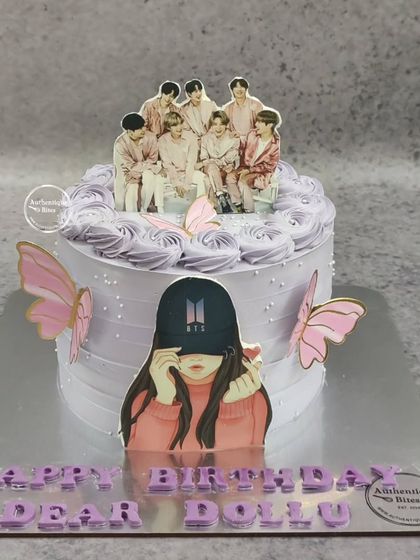A stylish cake for a BTS fan. This purple and white cake is decorated with butterflies and features toppers of the band and a fan avatar.