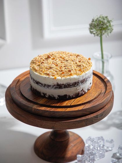 A simple yet elegant ice cream cake with a crumb topping, presented on a wooden stand. Sometimes, the simplest things are the most delicious.