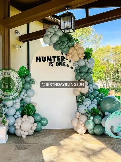 A "Hunter is One" dinosaur party with a gentle, modern aesthetic. The sage and mint green balloons and cute dinosaur cutouts are perfect for a first birthday.