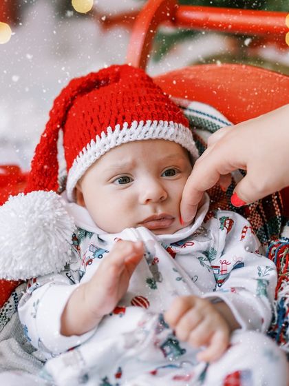 A close-up of the newborn baby in his Santa hat, looking so tiny and precious in the festive setup.
