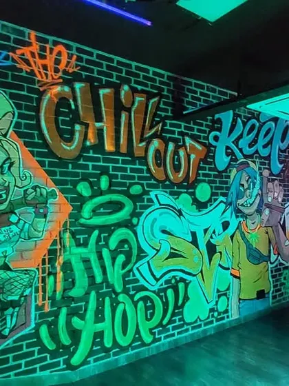This UV-reactive mural was a dope project for a gaming lounge. The neon graffiti, featuring characters like Harley Quinn, comes alive under blacklight, creating an immersive, edgy atmosphere.