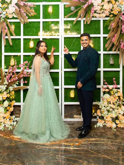 The couple posing in front of a modern, stylish green wall with a neon sign. This photo shows how I incorporate unique venue decor into your portraits.