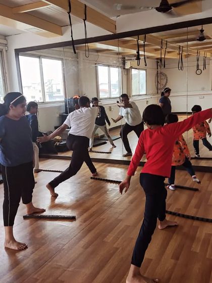 Students practice the 'ginga' in unison, following the instructor's lead in front of a mirror. This helps them learn proper form and timing.