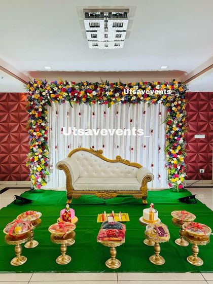 A wider view of the baby shower stage with the colorful floral arch, showing how it creates a grand and festive atmosphere in the event hall.