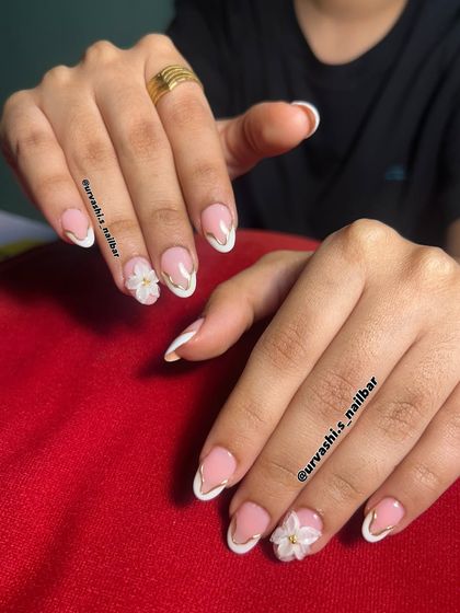 I love adding a touch of luxury to a classic French manicure. Here, I outlined the white tips with a fine gold line and added small 3D flowers for a look that's perfect for an engagement or pre-wedding shoot.