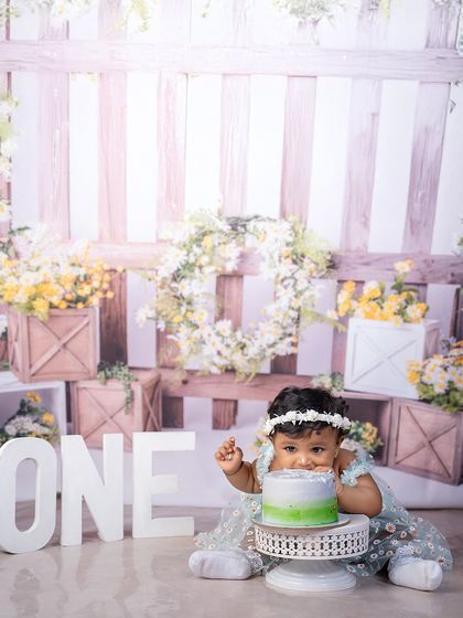 A close-up of the birthday girl enjoying her cake. The rustic garden theme with white and yellow flowers provides a beautiful, natural-feeling backdrop for this sweet moment.