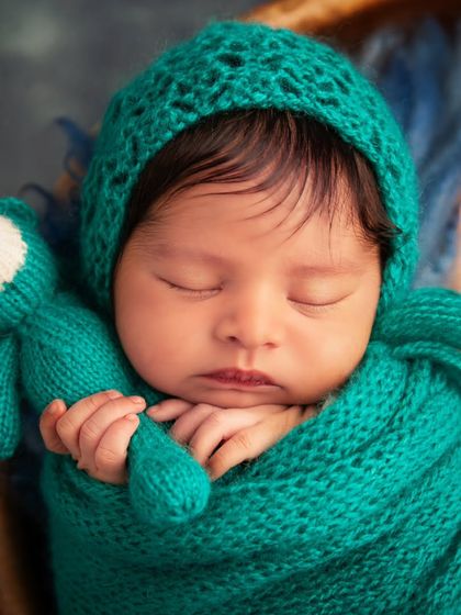 This detailed macro shot focuses on the baby's perfect features while sleeping. It highlights the texture of the knit bonnet and the baby's tiny hand holding the bear.