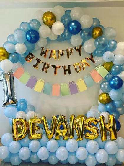 A simple and sweet setup for Devansh's first birthday, with a pastel-colored banner inside the balloon arch.