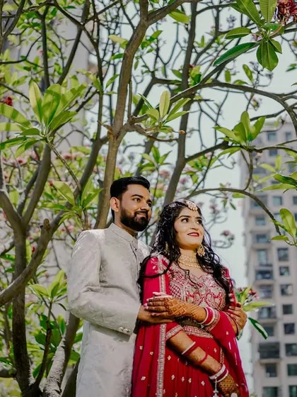 A beautiful portrait of the couple standing under a tree. The natural light filtering through the leaves creates a soft and romantic atmosphere.