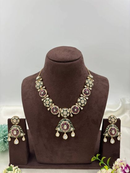 A unique necklace with a pendant featuring green and red Meenakari work, perfect for adding a pop of color.