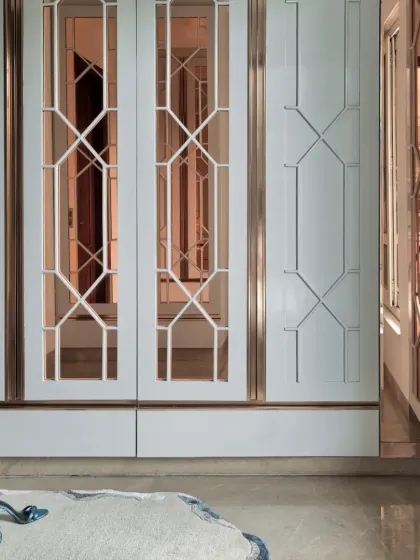 The walk-in wardrobe at The Classic Modern Storey features a subtle teal finish and mirrored panels with classic geometric patterns. This design enhances the sense of space while adding a touch of luxury and timeless charm.