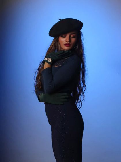 A classic fashion pose in the studio. The colored background and elegant styling result in a sophisticated and timeless portrait.