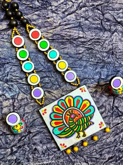 Here, the block-printed peacock is on a square pendant, offering a more geometric take on the design. The vibrant colors and folk-art style make it a very eye-catching piece.