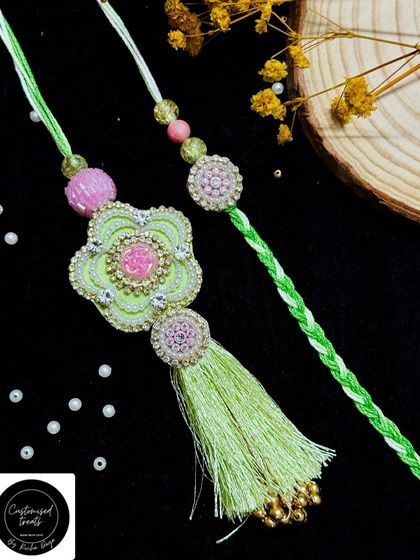 A lovely pastel green floral rakhi set. The Lumba features a large flower with a long tassel, paired with a matching smaller rakhi for a coordinated look.