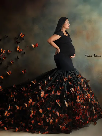 A touch of fantasy for your maternity shoot. This elegant black mermaid gown is elevated with a magical butterfly effect, creating a whimsical and artistic portrait that feels like a dream.
