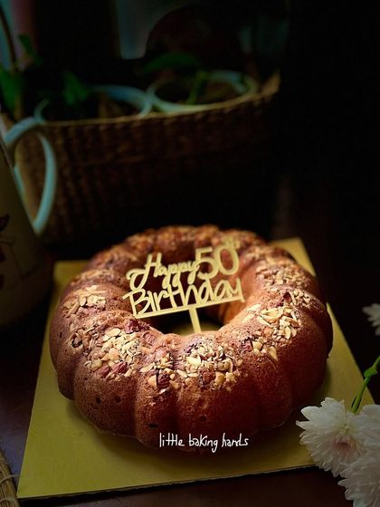 A French vanilla butter cake with nuts, baked in a bundt pan and topped with a "Happy 50th Birthday" sign. A classic and elegant cake for a milestone celebration.