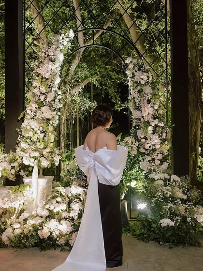 For a glamorous bachelorette, we designed a Chanel-inspired welcome dinner. This moment captures the chic elegance of the event, with a custom gown echoing the dramatic floral arch, blending high fashion with our bespoke floral artistry.