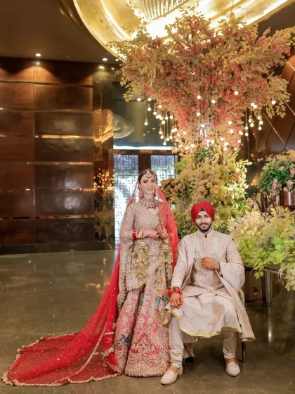 A regal portrait of the couple against a magnificent floral and light installation. This shot showcases both their stunning attire and the beautiful wedding decor.
