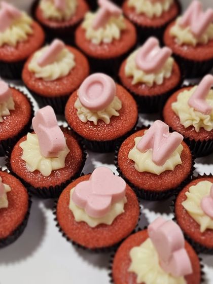 A close-up of our custom whole wheat red velvet cupcakes. Each mini cupcake is topped with cream cheese frosting and a personalized chocolate letter.