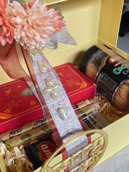 A closer look at the pearl-studded ribbon and floral decoration on the Diwali hamper. It's these handcrafted details that elevate the gift.