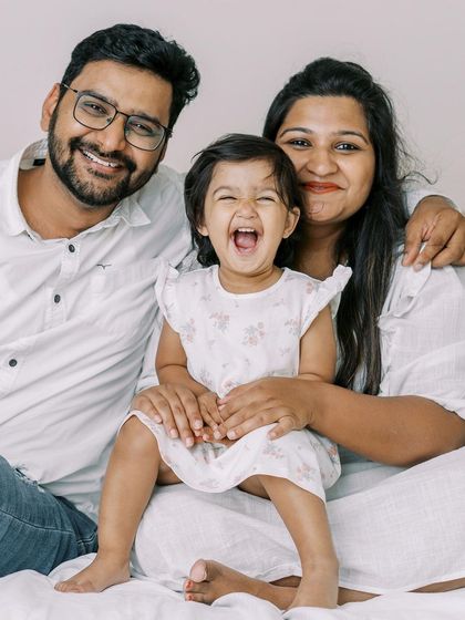 A family laughing together on the bed. This is what a successful session looks like: genuine joy and connection.